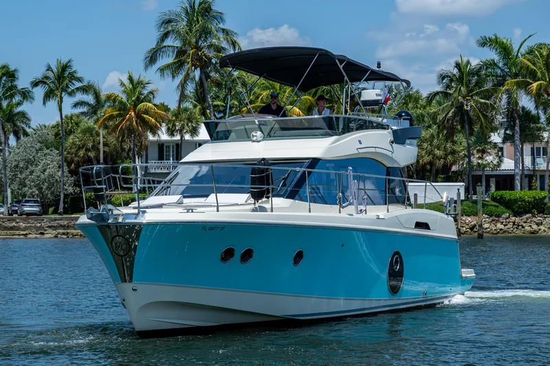 Slide: The Image of 2015 Beneteau MONTE CARLO yacht cruising on a sunny day with palm trees in the background. - 2