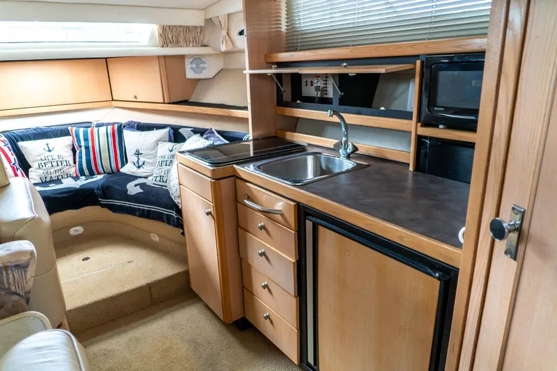 Slide: The Image of Interior of 1998 Bayliner 3255 Avanti boat with kitchenette and cozy seating area. - 13