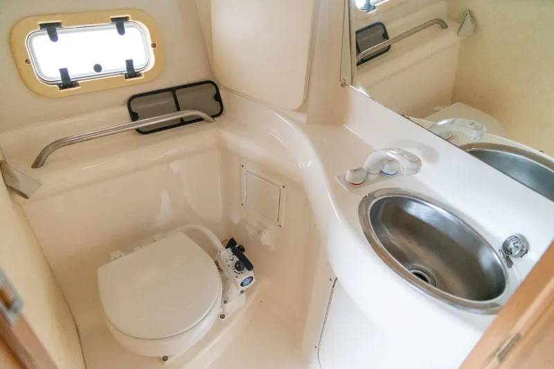 Slide: The Image of 1998 Bayliner 3255 Avanti boat bathroom with toilet, sink, and porthole window. - 17