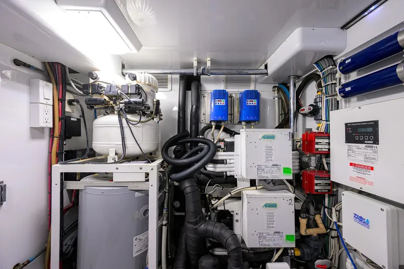 Slide: The Image of Engine room of a 2003 American Custom Yachts Sport Fisherman, showcasing complex machinery and wiring. - 66