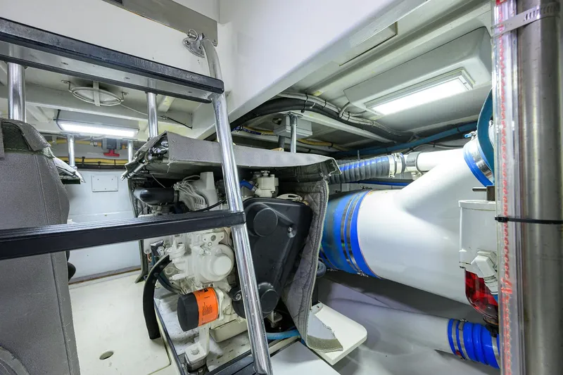Slide: The Image of Engine room of a 2003 American Custom Yachts Sport Fisherman, featuring mechanical components and piping. - 69