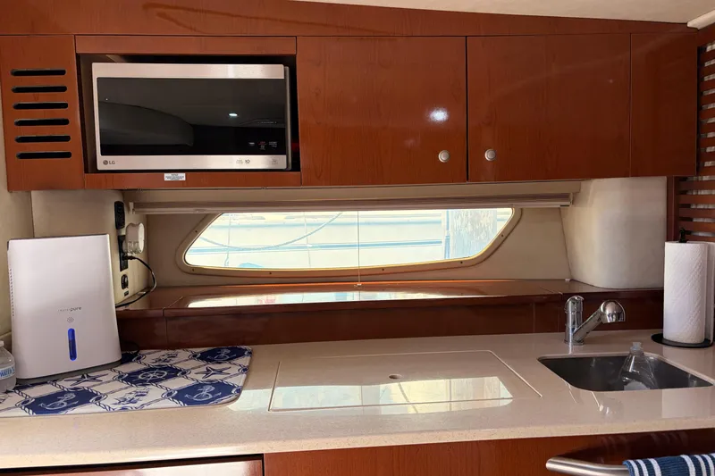 Slide: The Image of 2008 Sea Ray Sundancer 350 yacht kitchen with microwave, sink, and wooden cabinets. - 25