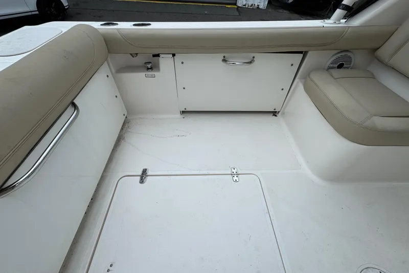 Slide: The Image of 2016 Pursuit DC 265 Dual Console boat interior with beige seating and storage compartments. - 16