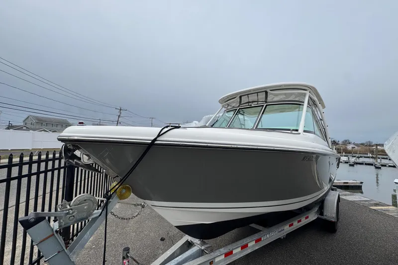 Slide: The Image of 2016 Pursuit DC 265 Dual Console boat on trailer near marina. - 2