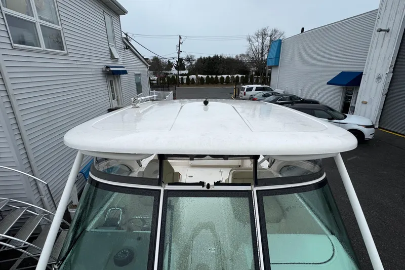 Slide: The Image of 2016 Pursuit DC 265 Dual Console boat parked near buildings and cars. - 6