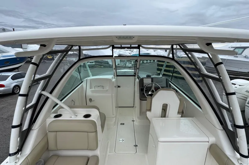 Slide: The Image of 2016 Pursuit DC 265 Dual Console boat interior with seating and helm, docked outdoors. - 7