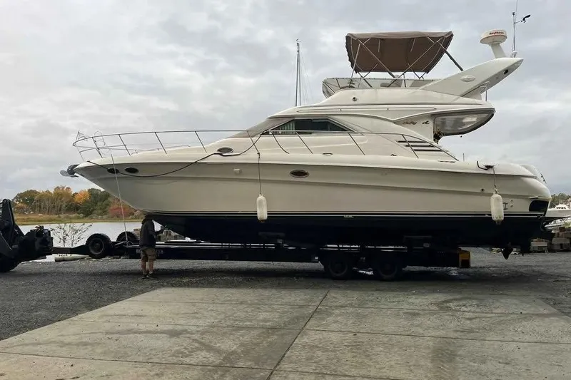 The Image of 1997 Sea Ray 400 Sedan Bridge yacht on trailer by waterfront. - 0