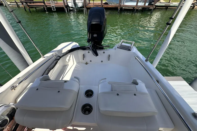 Slide: The Image of 2023 Boston Whaler 13 SS boat interior with seating and motor, docked on calm water. - 8