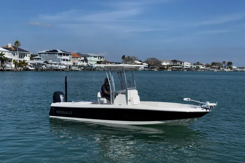 Slide: The Image of 2015 Robalo 226 Cayman boat on calm water near coastal homes. - 12