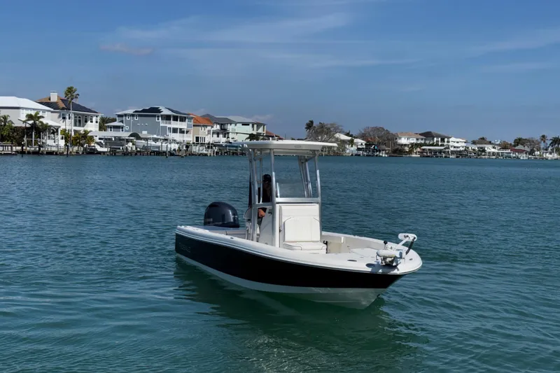Slide: The Image of 2015 Robalo 226 Cayman boat on calm water near coastal homes. - 14