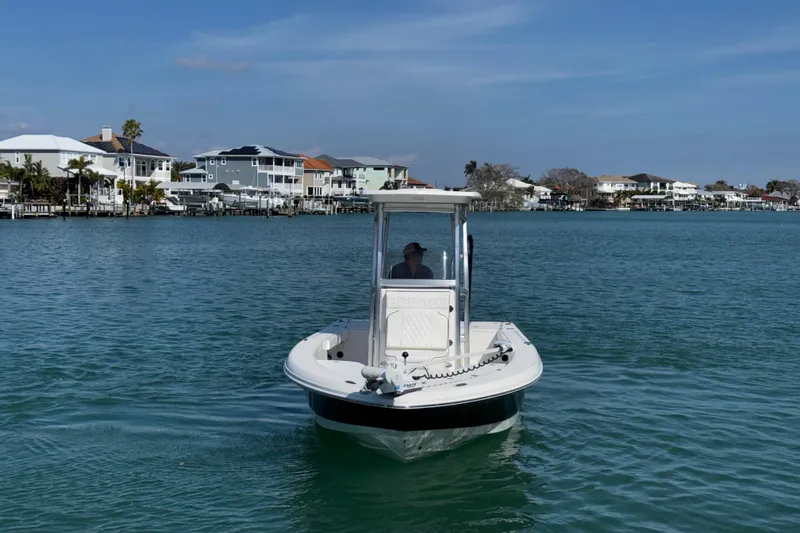 Slide: The Image of 2015 Robalo 226 Cayman boat cruising on a calm waterway near waterfront homes. - 16