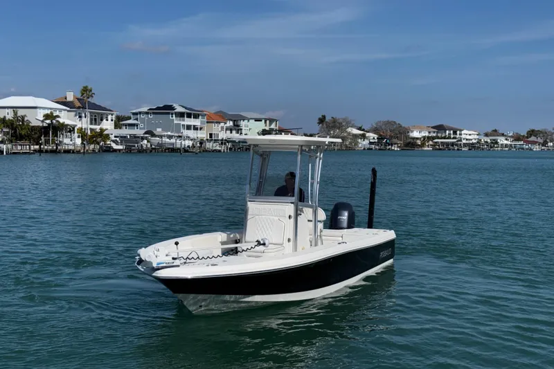 Slide: The Image of 2015 Robalo 226 Cayman boat cruising on a calm waterfront with houses in the background. - 17