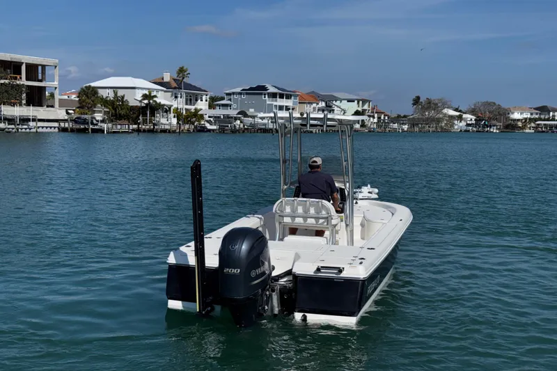 Slide: The Image of 2015 Robalo 226 Cayman boat cruising on a calm waterfront with houses in the background. - 2