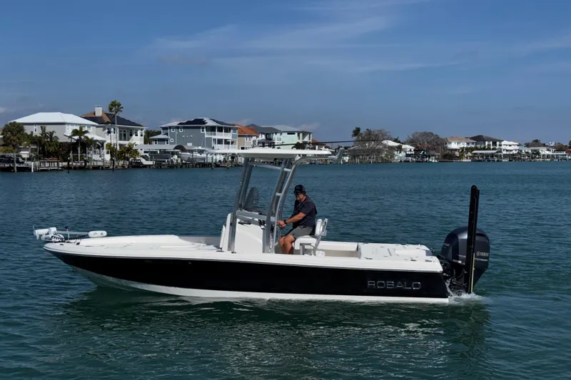 Slide: The Image of 2015 Robalo 226 Cayman boat cruising on a calm waterway near waterfront homes. - 20