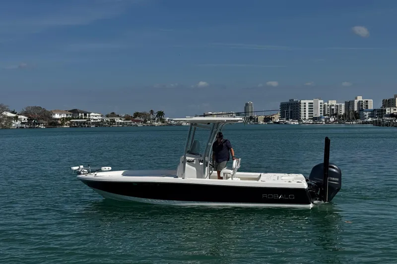 Slide: The Image of 2015 Robalo 226 Cayman boat on calm water with cityscape background. - 22