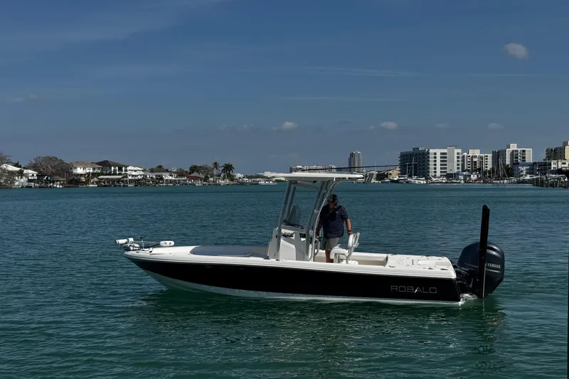 Slide: The Image of 2015 Robalo 226 Cayman boat on calm water with cityscape background. - 23