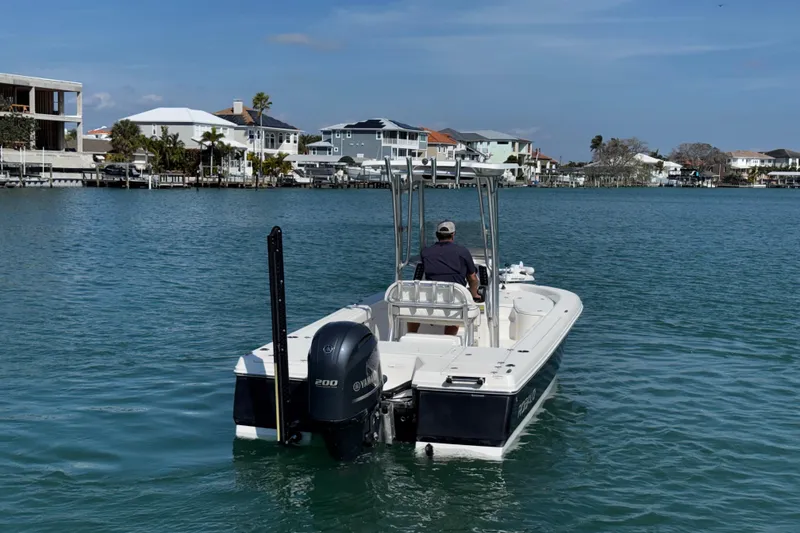 Slide: The Image of 2015 Robalo 226 Cayman boat cruising on a calm waterfront with houses in the background. - 3