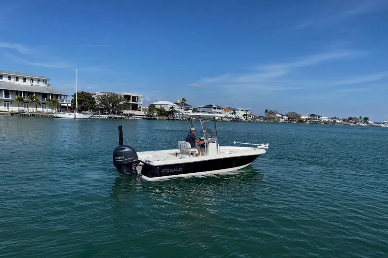 Slide: The Image of 2015 Robalo 226 Cayman boat cruising on a sunny day near waterfront homes. - 6