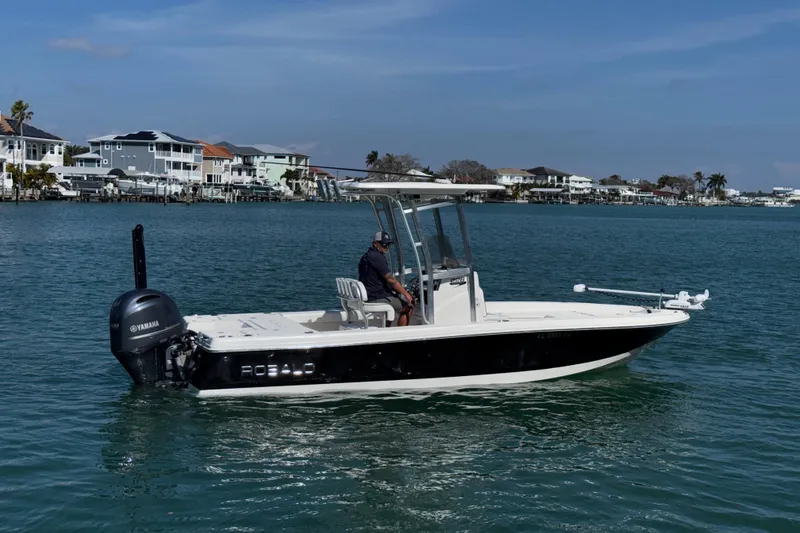 Slide: The Image of 2015 Robalo 226 Cayman boat on calm water with coastal houses in the background. - 8