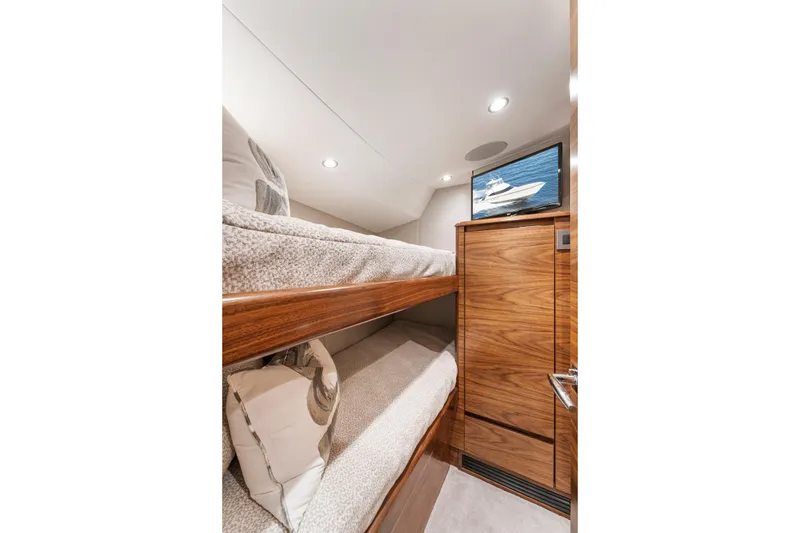 Slide: The Image of Interior of 2026 Viking 50 Convertible yacht with cozy bunk beds and wooden cabinetry. - 15
