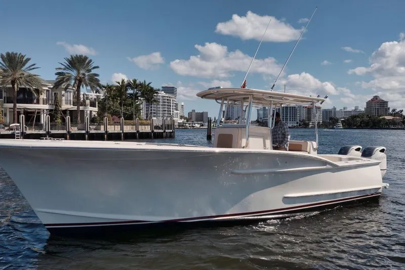 The Image of 2019 Custom Carolina boat cruising near waterfront homes under a clear blue sky. - 1