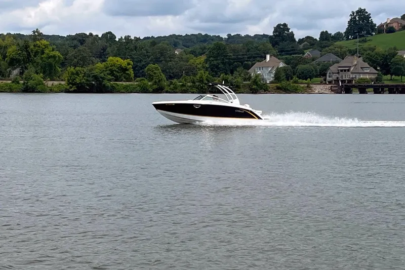 The Image of 2015 Cobalt R5 boat cruising on a scenic lake with houses in the background. - 1