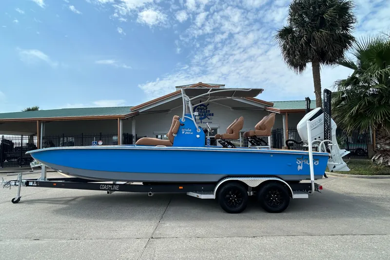 The Image of 2026 Skuta 24 Skuta Cat boat on trailer, blue hull, parked outdoors. - 0