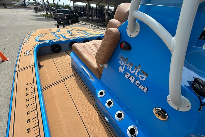 Slide: The Image of Blue 2026 Skuta 24 Cat boat with tan seating and detailed deck design. - 16