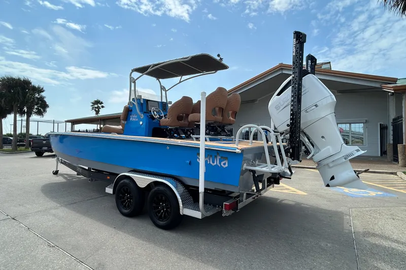 Slide: The Image of 2026 Skuta 24 Skuta Cat boat on trailer, blue exterior, parked outdoors. - 6