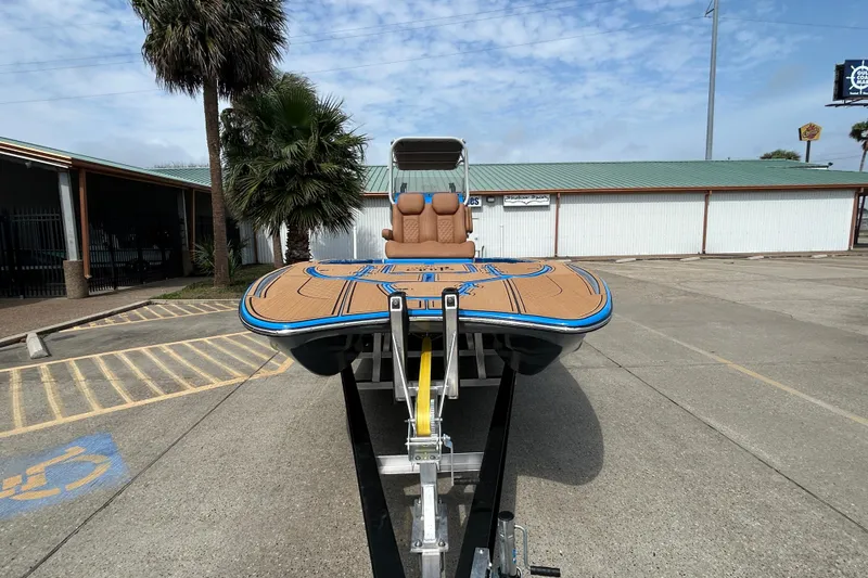 Slide: The Image of 2026 Skuta 24 Skuta Cat boat on trailer, parked outdoors with palm trees. - 7