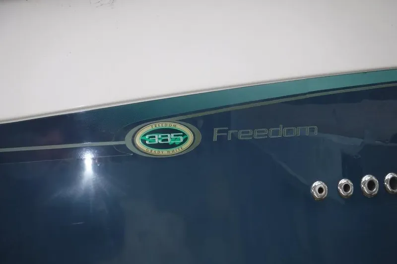 Slide: The Image of 2014 Grady-White Freedom 335 boat emblem on blue and white hull. - 22