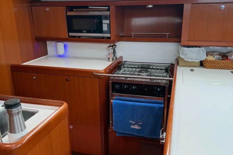 Slide: The Image of Galley kitchen in 2007 Beneteau 49 yacht with stove, microwave, and wooden cabinetry. - 5