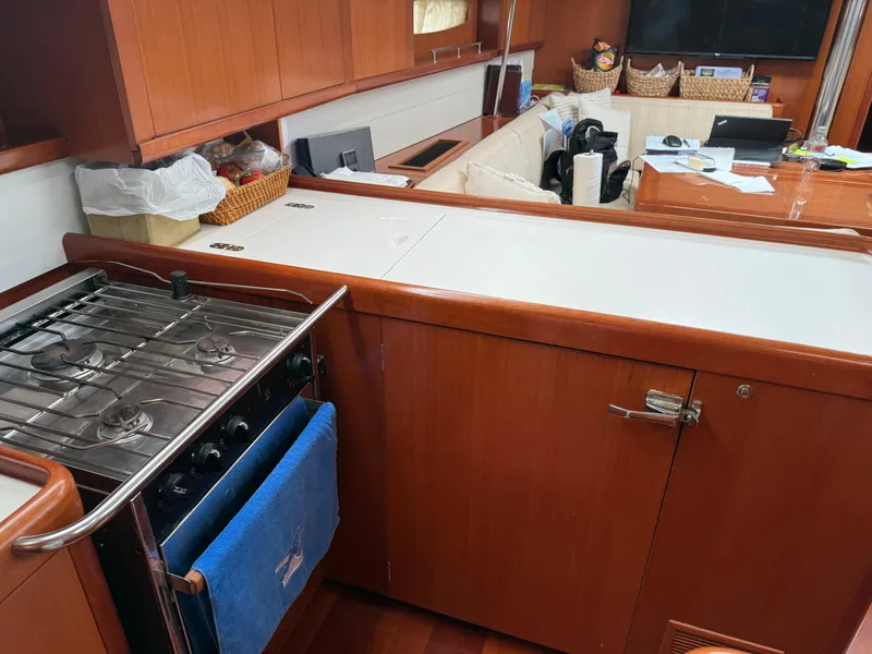 Slide: The Image of Interior of 2007 Beneteau 49 yacht kitchen with stove, wooden cabinetry, and seating area. - 6