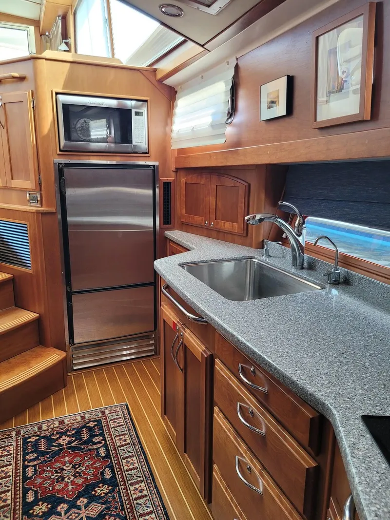 Slide: The Image of 2014 Sabre 48 Salon Express kitchen with stainless steel appliances and wooden cabinetry. - 9