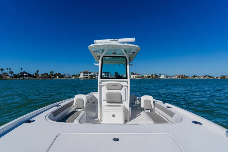 Slide: The Image of 2022 Caymas 28 HB boat cruising on clear blue water near coastal homes. - 14