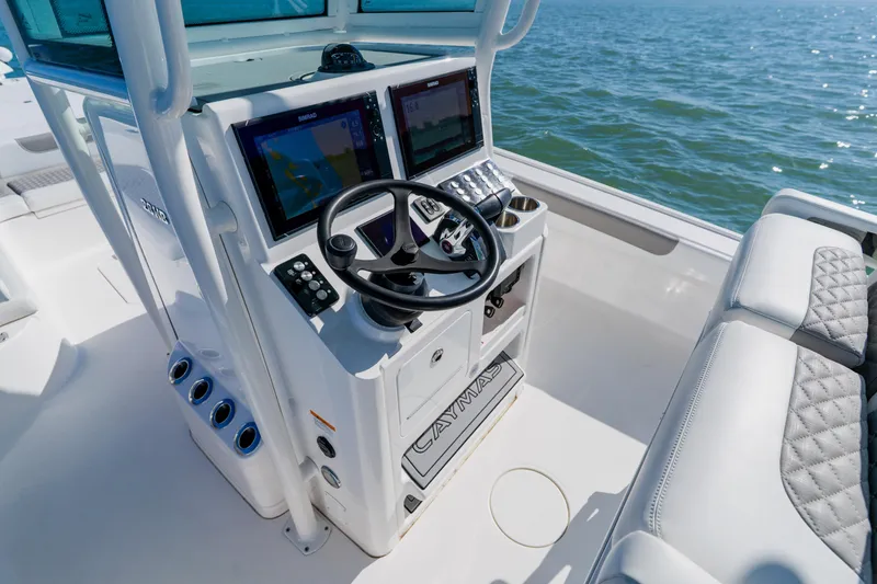 Slide: The Image of 2022 Caymas 28 HB boat helm with dual displays and steering wheel on open water. - 23