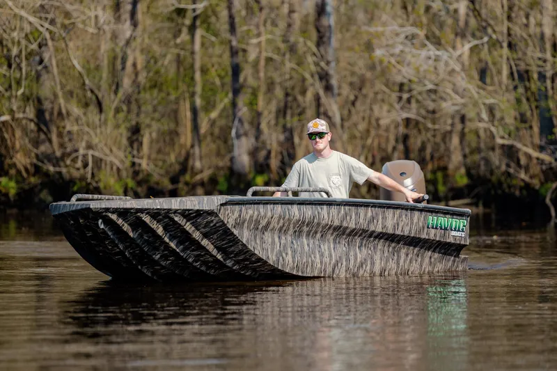 Slide: The Image of 2026 Havoc 1756 DBST boat navigating a calm river with a forest backdrop. - 10