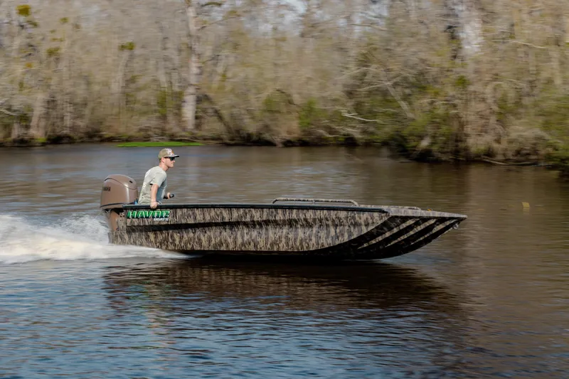 Slide: The Image of 2026 Havoc 1756 DBST boat cruising on a river with a forested background. - 2
