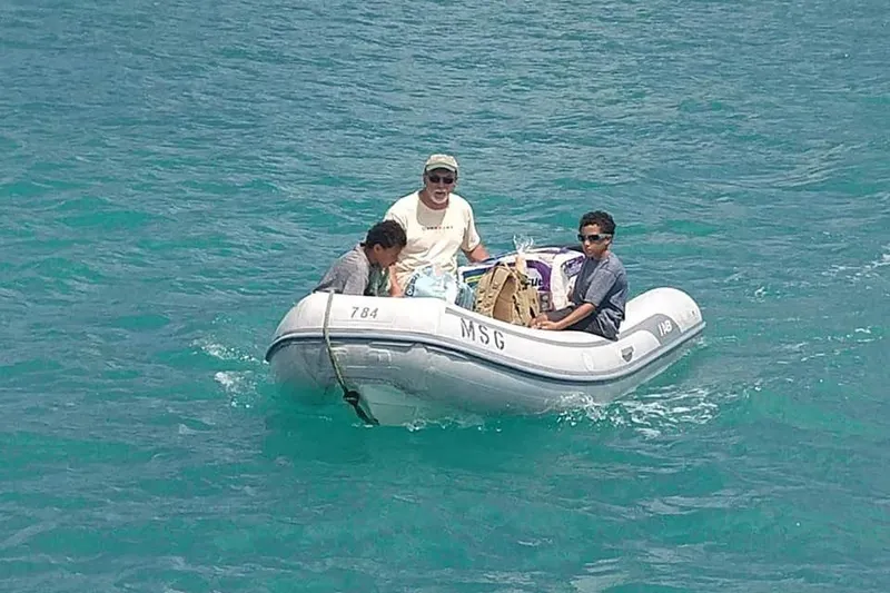 Slide: The Image of Three people in a small inflatable boat on clear blue water. - 19