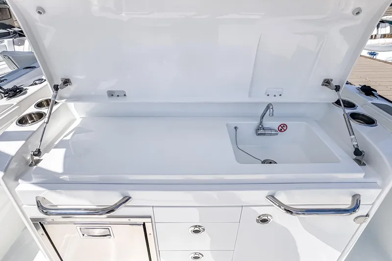 Slide: The Image of 2026 Wellcraft 28 T-Top boat sink and storage area with open lid. - 9