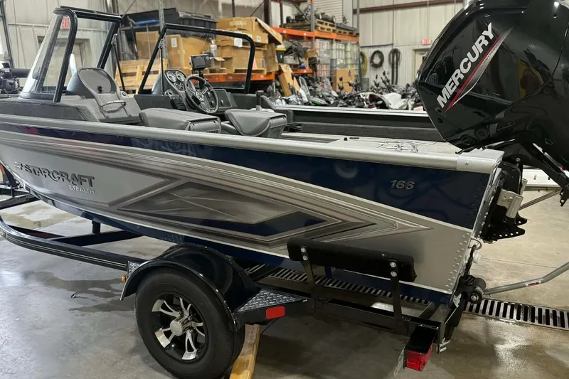 Slide: The Image of 2023 Starcraft Stealth 166 DC boat with Mercury engine in a warehouse setting. - 2