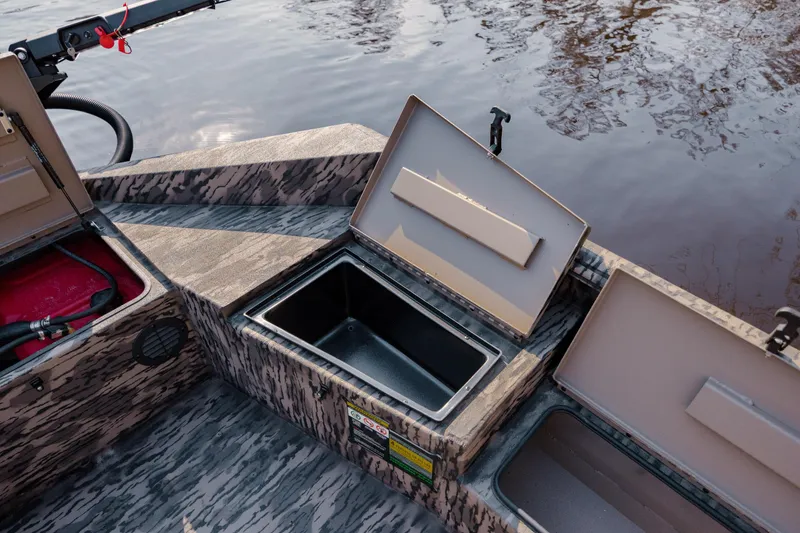 Slide: The Image of Open storage compartments on a 2026 Havoc 1756 MSTC boat by the water. - 22