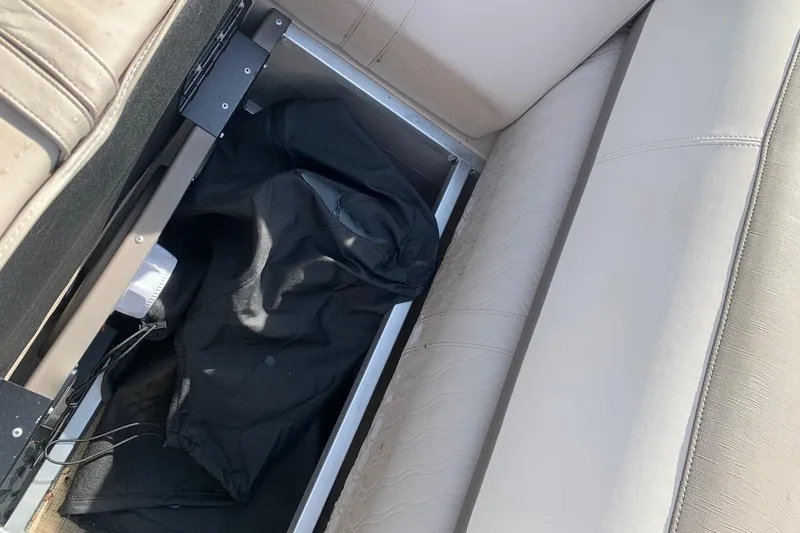 Slide: The Image of 2024 Avalon Catalina Quad Lounge storage compartment with black cover and beige seating. - 20