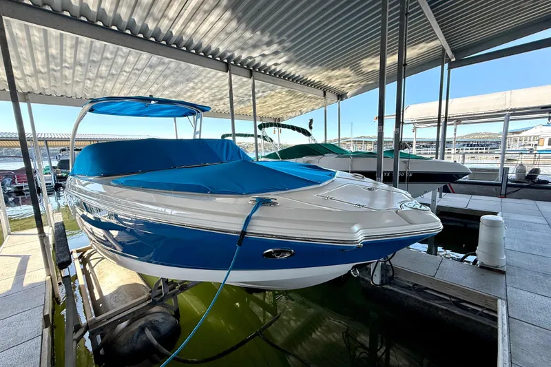 Slide: The Image of 2017 Chaparral 246 SSi boat docked under a covered marina, featuring a blue cover. - 13