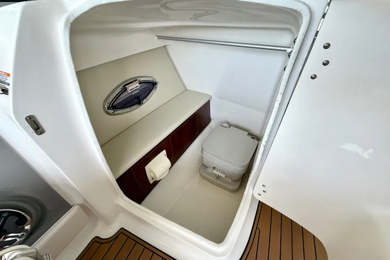 Slide: The Image of 2017 Chaparral 246 SSi boat interior with compact toilet and storage area. - 25