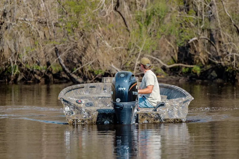 Slide: The Image of Man navigating Excel 183 Tomahawk boat on calm river, surrounded by trees. - 12