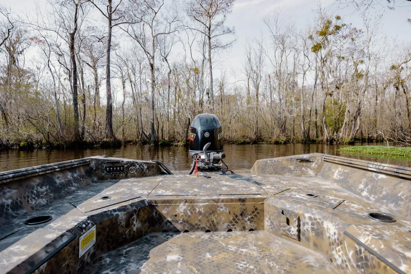 Slide: The Image of Camouflage-patterned Excel 183 Tomahawk boat navigating a serene, tree-lined waterway. - 18