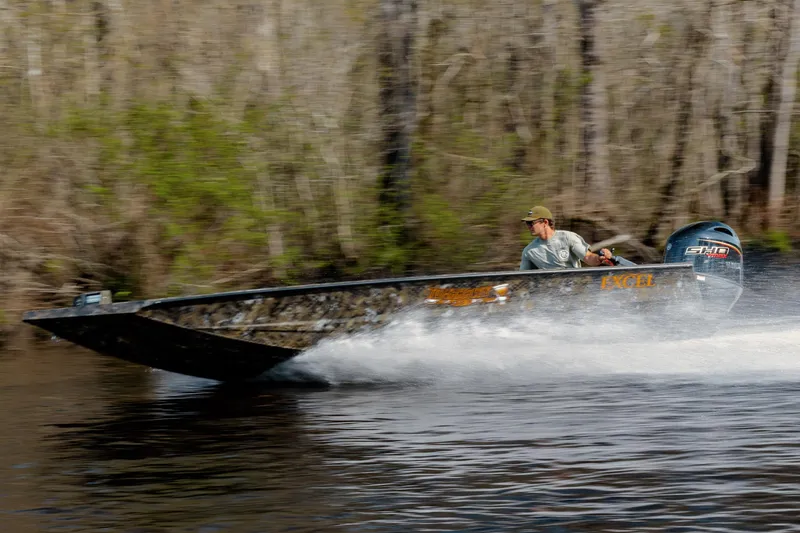 Slide: The Image of 2026 Excel 183 Tomahawk boat speeding on a river with a forest backdrop. - 7
