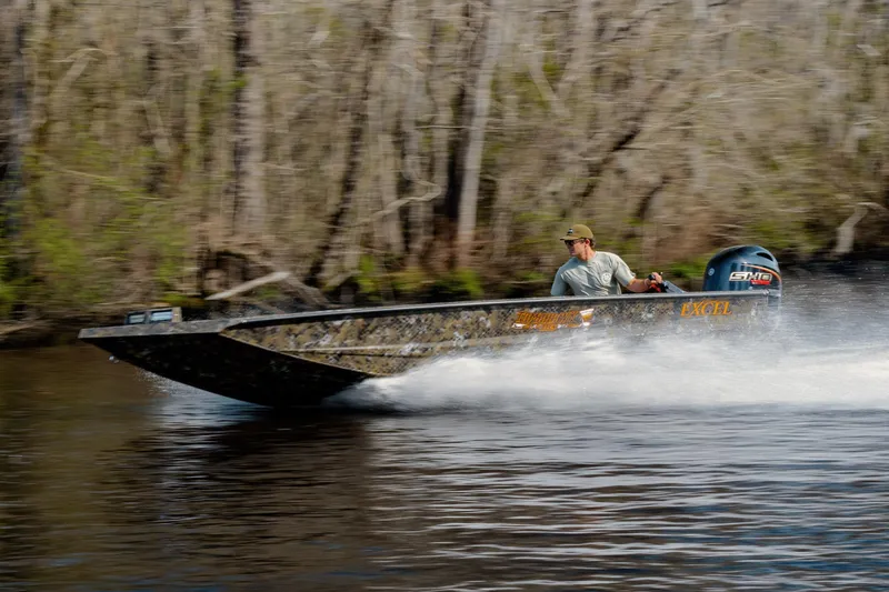 Slide: The Image of 2026 Excel 183 Tomahawk boat speeding on a river with forest backdrop. - 8