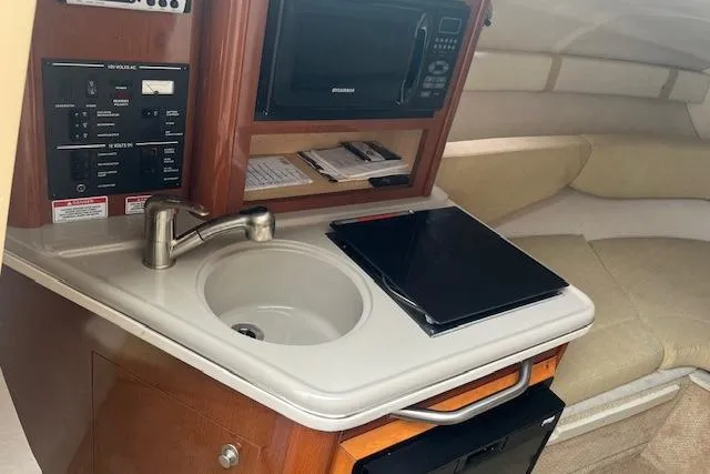 Slide: The Image of 2008 Sea Ray 240 Sundancer cabin with kitchenette, sink, microwave, and seating area. - 13